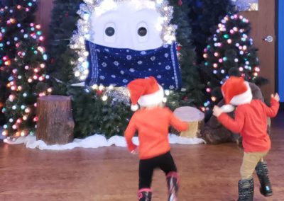 Two children dancing with Bruce the Spruce