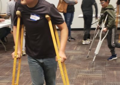 Students practice walking on crutches after learning about Civil War era medical practices.