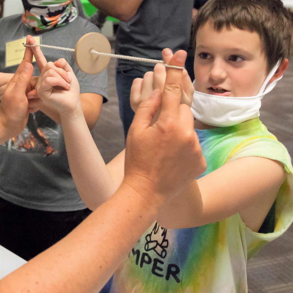 A Sheboygan elementary student learns how to spin a wooden "buzz saw" in the Full-Day Education Program at the Sheboygan History Museum